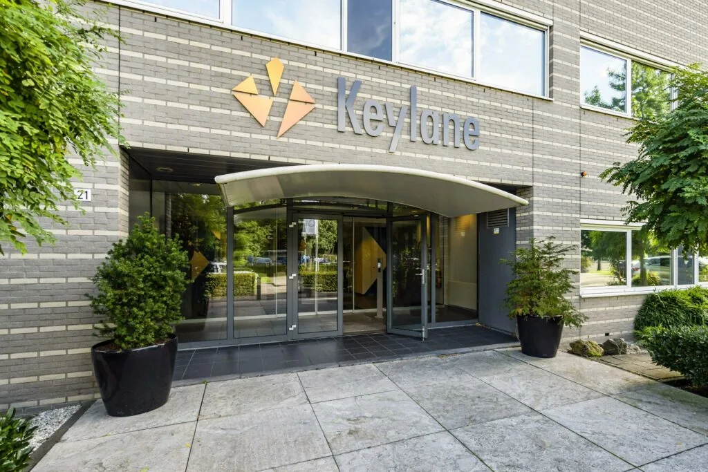 Ingang van het Keylane-kantoor aan de Jan Leentvaarlaan, met glazen deuren en bedrijfslogo op de gevel.